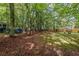 Large backyard with mature trees, grass area, and a small wooden fence at 3927 Collier Nw Trce, Kennesaw, GA 30144