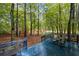 View of the wooded backyard, deck with outdoor seating and shade trees at 3927 Collier Nw Trce, Kennesaw, GA 30144