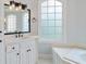 Bright bathroom with light countertops, modern lighting, and a tub with tile surround at 5041 Corinault Nw Pl, Acworth, GA 30101
