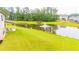Spacious backyard with a pond featuring a fountain, covered patio, and mature tree line at 6390 Yellow Birch St, Cumming, GA 30040