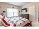 Comfortable bedroom with a TV over a brown dresser and a bed with a white and red cover at 6390 Yellow Birch St, Cumming, GA 30040
