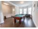 A well-lit and open space featuring a billiard table, hardwood floors, and multiple windows at 6390 Yellow Birch St, Cumming, GA 30040