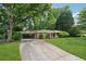 Well-maintained single story home showcasing a lovely front lawn, mature trees, and a covered parking area at 500 Read Ln, Atlanta, GA 30328