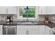 Kitchen featuring white cabinets, mosaic backsplash, stainless steel appliances, and a garden window at 500 Read Ln, Atlanta, GA 30328