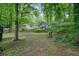 View of the home and yard with mature trees, a fenced-in yard and serene greenery at 588 Benson Hurst Sw Dr, Mableton, GA 30126