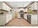 Well-lit kitchen has white cabinets, stainless steel appliances, and tile flooring at 588 Benson Hurst Sw Dr, Mableton, GA 30126
