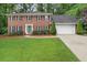 Classic brick home with a well-manicured lawn, mature trees, and a two-car garage at 4507 Reva Way, Marietta, GA 30066