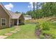 Lush green backyard with a stone path, flowering plants, and a covered patio area at 59 Grand Georgian Ne Ct, Cartersville, GA 30121