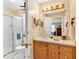 Bathroom vanity with wood cabinets, a sink, mirror with lighting, and glass enclosed shower at 712 Honeysuckle Ln, Temple, GA 30179