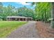Exterior view of a cozy single-story home with a long driveway surrounded by lush greenery and mature trees at 712 Honeysuckle Ln, Temple, GA 30179
