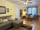 Comfortable living room featuring a grey sofa, decorative pillows, and a view of the dining area at 712 Honeysuckle Ln, Temple, GA 30179