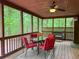 The screened porch includes a table with red chairs, a ceiling fan, and forest views at 712 Honeysuckle Ln, Temple, GA 30179