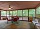 Relaxing screened-in porch with wood flooring, seating area, and view of backyard greenery at 712 Honeysuckle Ln, Temple, GA 30179