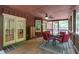 Comfortable screened-in porch with dark wood paneling, red chairs, and ceiling fan at 712 Honeysuckle Ln, Temple, GA 30179