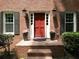 Charming brick home entryway with a red front door, stylish lanterns, and well-manicured landscaping at 4673 Jefferson Township Pl, Marietta, GA 30066
