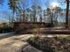 Exterior view of a brick home with a green door and a driveway, surrounded by tall trees and natural landscaping at 1053 Allgood Rd, Stone Mountain, GA 30083