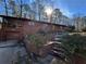 Exterior view of a brick home with a garage and a green door, surrounded by tall trees and natural landscaping at 1053 Allgood Rd, Stone Mountain, GA 30083