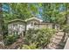 View of the back of the house showing the deck, stairs, lower level entry, and mature landscaping at 6590 Williamson Ne Dr, Atlanta, GA 30328