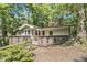 Home exterior with a wooden deck entrance, situated among lush trees and a wooded yard at 6590 Williamson Ne Dr, Atlanta, GA 30328