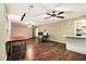 Open living room with dark floors, ceiling fans, wood paneled walls, and connected kitchen with granite countertops at 6590 Williamson Ne Dr, Atlanta, GA 30328