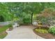 Inviting backyard patio with a decorative fountain, white garden furniture, and lush landscaping at 11190 Hembree Springs Dr, Roswell, GA 30076