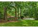 Lovely backyard with mature trees, well manicured lawn, and a charming white fence at 11190 Hembree Springs Dr, Roswell, GA 30076