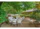 A backyard with a peaceful patio setting featuring white wicker furniture, lush greenery, and a white picket fence at 11190 Hembree Springs Dr, Roswell, GA 30076