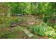 Well-maintained backyard garden area with a potting bench, mature trees, and a peaceful seating area at 11190 Hembree Springs Dr, Roswell, GA 30076