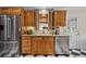 A kitchen featuring wood cabinets, stainless steel appliances, tile backsplash, and black and white tile floor at 11190 Hembree Springs Dr, Roswell, GA 30076