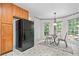 Charming kitchen nook with black refrigerator, wooden cabinets, table, and view of wooded backyard at 3 Maplelake Dr, Acworth, GA 30101