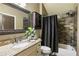 Cozy bathroom with granite countertops, decorative mirror, and tiled shower with stylish curtain at 4830 Westgate Dr, Cumming, GA 30040