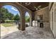 Spacious covered patio with stone flooring, brick arches, and a built-in stainless steel grill at 4830 Westgate Dr, Cumming, GA 30040