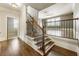 Elegant staircase with hardwood steps, wrought iron railing, and views into a spacious living area with lots of light at 4830 Westgate Dr, Cumming, GA 30040