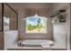 A large bathtub sits next to a window with a view of the outdoors, with decorative shelves overhead at 3825 Valleyway Rd, Cumming, GA 30040
