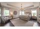 A well-lit bedroom with a decorative chandelier, gray toned furniture and hardwood floors at 3825 Valleyway Rd, Cumming, GA 30040