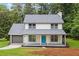 Charming two-story home with a welcoming front porch and a new gray roof, set amongst mature trees at 4657 Lou Ivy Rd, Peachtree Corners, GA 30096