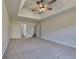 Spacious main bedroom with tray ceilings, a fan, carpet, and access to an en-suite bathroom at 5136 Estonian Dr, Fairburn, GA 30213