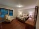 Comfortable bedroom with wood floors, a decorative wingback chair, and natural light at 1260 Willeo Creek Dr, Roswell, GA 30075