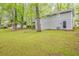 A large grassy backyard with trees; attached carport to a gray home; well-maintained yard at 3084 Fern Valley Sw Dr, Marietta, GA 30008