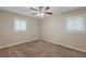 A well-lit bedroom with two windows and a ceiling fan, featuring plush carpeting and neutral walls at 3084 Fern Valley Sw Dr, Marietta, GA 30008