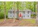 Charming two-story home with grey brick, black shutters, red door, and a covered parking area surrounded by lush trees at 3084 Fern Valley Sw Dr, Marietta, GA 30008