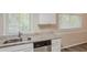 Close-up of a kitchen's sink, dishwasher, granite counters, and white cabinets with a window bringing in natural light at 3084 Fern Valley Sw Dr, Marietta, GA 30008