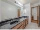 A bathroom featuring dual sinks, a large mirror, and an open doorway at 3835 Shawnee Sw Run, Lilburn, GA 30047