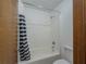 Standard white bathtub with shower and striped curtain in a basic, functional bathroom at 3835 Shawnee Sw Run, Lilburn, GA 30047