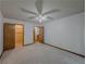 An open bedroom with a ceiling fan, neutral carpet, and natural wood doors at 3835 Shawnee Sw Run, Lilburn, GA 30047