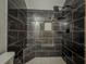 Modern shower with dark marbled tile, built in shelving and a rain shower head at 3835 Shawnee Sw Run, Lilburn, GA 30047