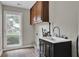 This laundry room features wood cabinets, a sink, and a window for added convenience at 5950 Meadow Brook Ln, Cumming, GA 30040