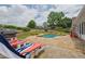 Backyard patio area featuring lounge chairs and a grill with a view of the swimming pool and landscaped yard at 5950 Meadow Brook Ln, Cumming, GA 30040