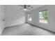 Sunlit bedroom with neutral carpeting, two large windows, a ceiling fan, and white trim throughout at 1265 Kelly Nelson Dr, Lawrenceville, GA 30043