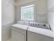 Functional laundry room with washer, dryer, storage shelves, and a bright window at 1265 Kelly Nelson Dr, Lawrenceville, GA 30043